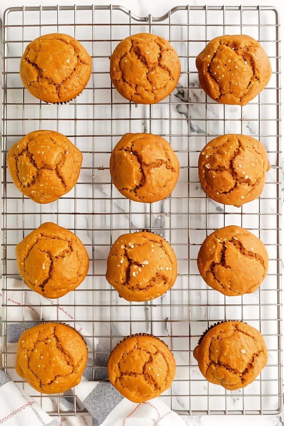 Two-Ingredient Pumpkin Muffins Cooling on a Wire Rack on a White Marble Table