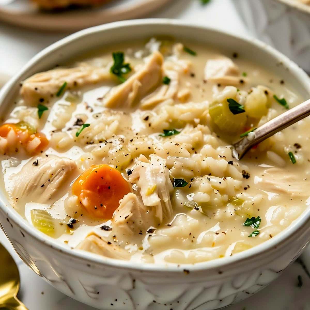 Close up Creamy Chicken Rice Soup in a White Bowl with a Spoon