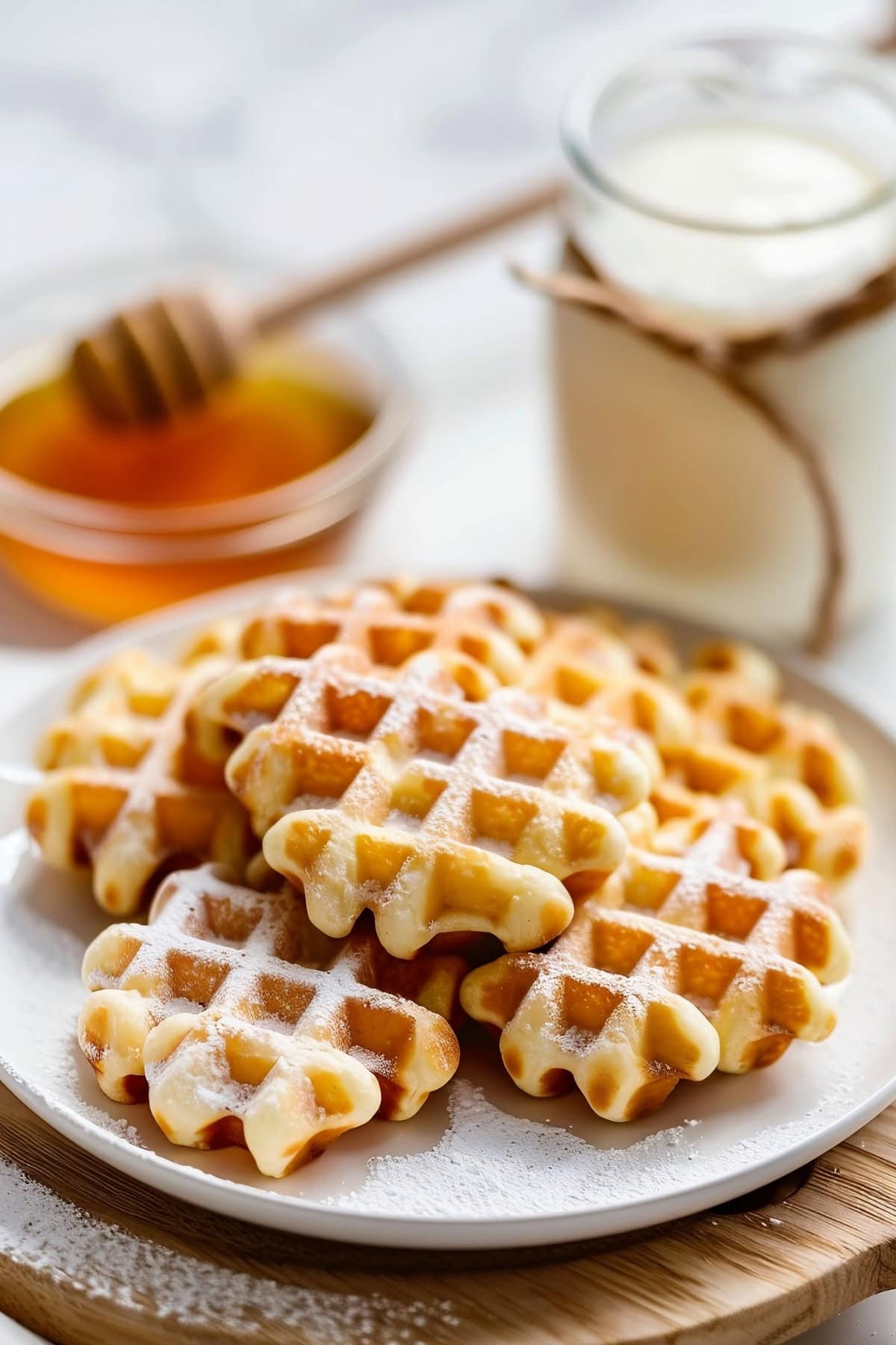 Close Up of Waffle Cookies on a Plate with Milk and Honey in the Background