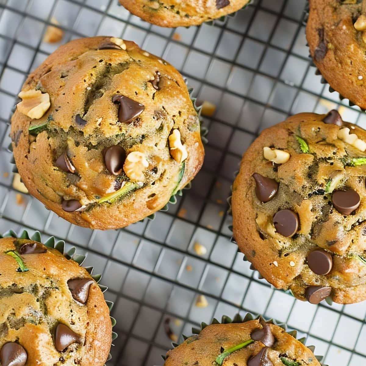 Top View of Perfectly Baked Zucchini Chocolate Chip Muffins with Visible Chocolate Chips, Walnuts, and Zucchini Bits Cooling on a Wire Rack