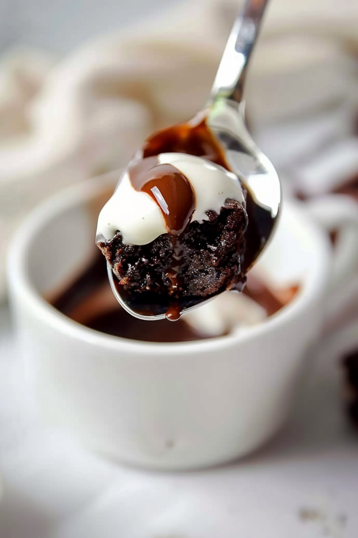 Close-up shot of a spoonful of hot chocolate mug cake with ice cream and chocolate sauce on top.