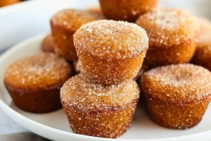 Cinnamon sugar coated apple cider donut muffins in a white plate.