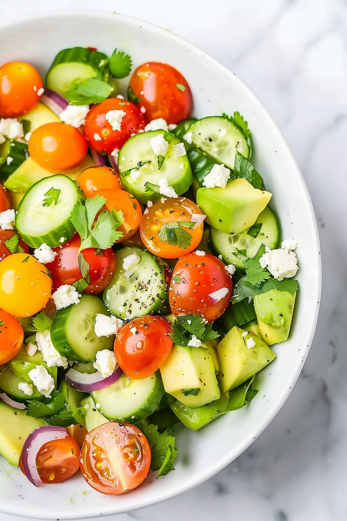 Homemade avocado salad with cucumber, cherry tomatoes and crumbled feta cheese.