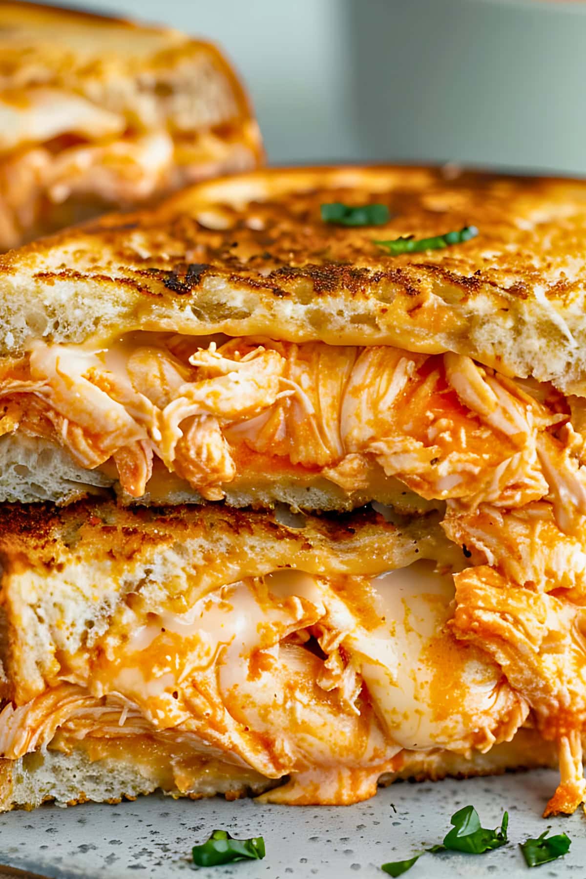 Close up of Buffalo Chicken Grilled Cheese sandwich cut in half and stacked on a chopping board