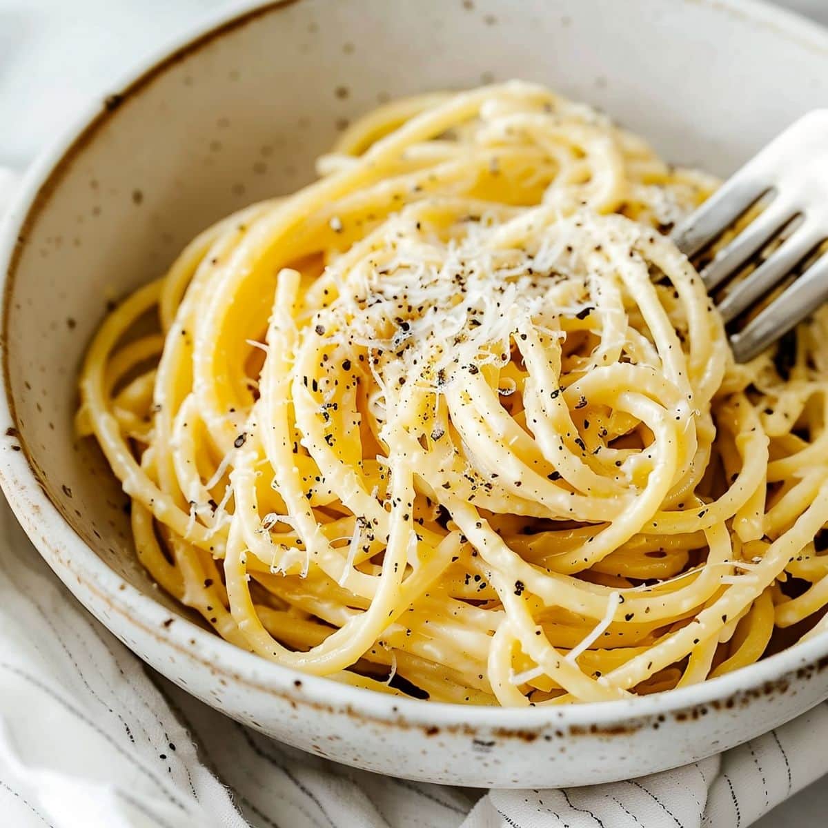 Super Close Up of Cacio e Pepe with Pepper and Cheese and a Fork in a Bowl