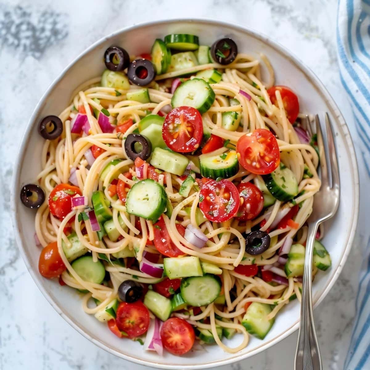 Colorful California pasta salad featuring cucumbers, cherry tomatoes and black olives.