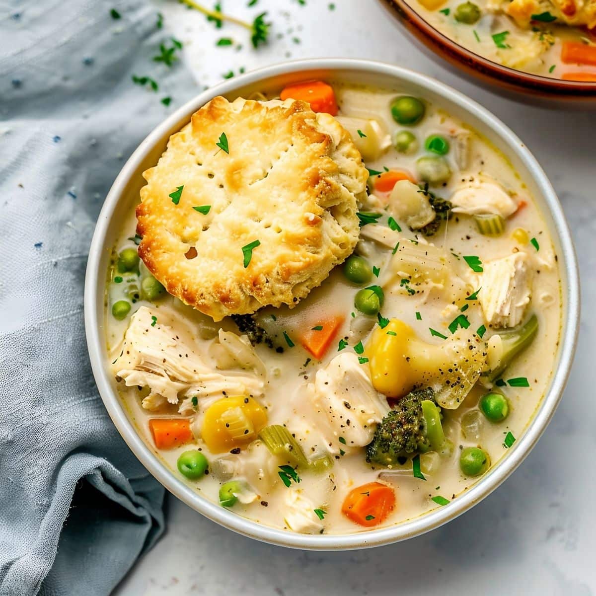 Top View of Two Bowls of Chicken Pot Pie Soup with a Biscuit on Top