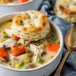 Bowls of Chicken Pot Pie Soup with Chicken, Carrots, Celery, Peas, Onions, and Corn, Served with Biscuits, Spoon to the Side