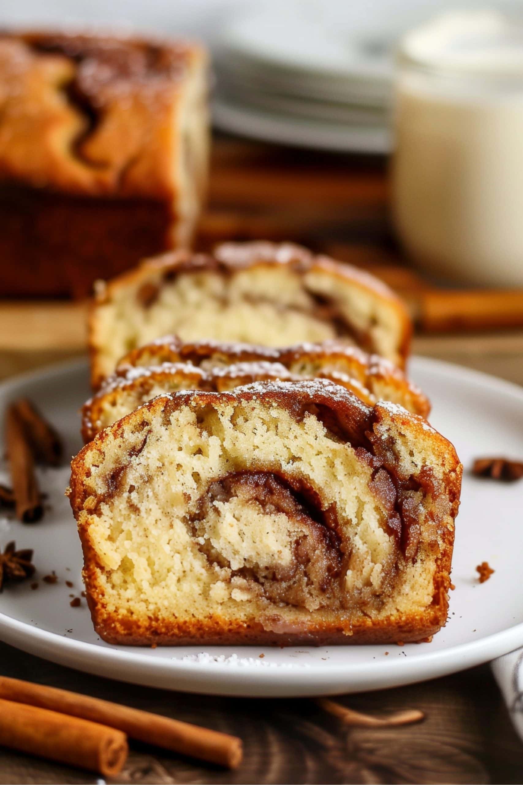 A close-up of a freshly baked cinnamon swirl quick bread, with its golden-brown crust in a white plate.