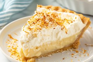 A perfect slice of coconut cream pie garnished with toasted coconut on top.