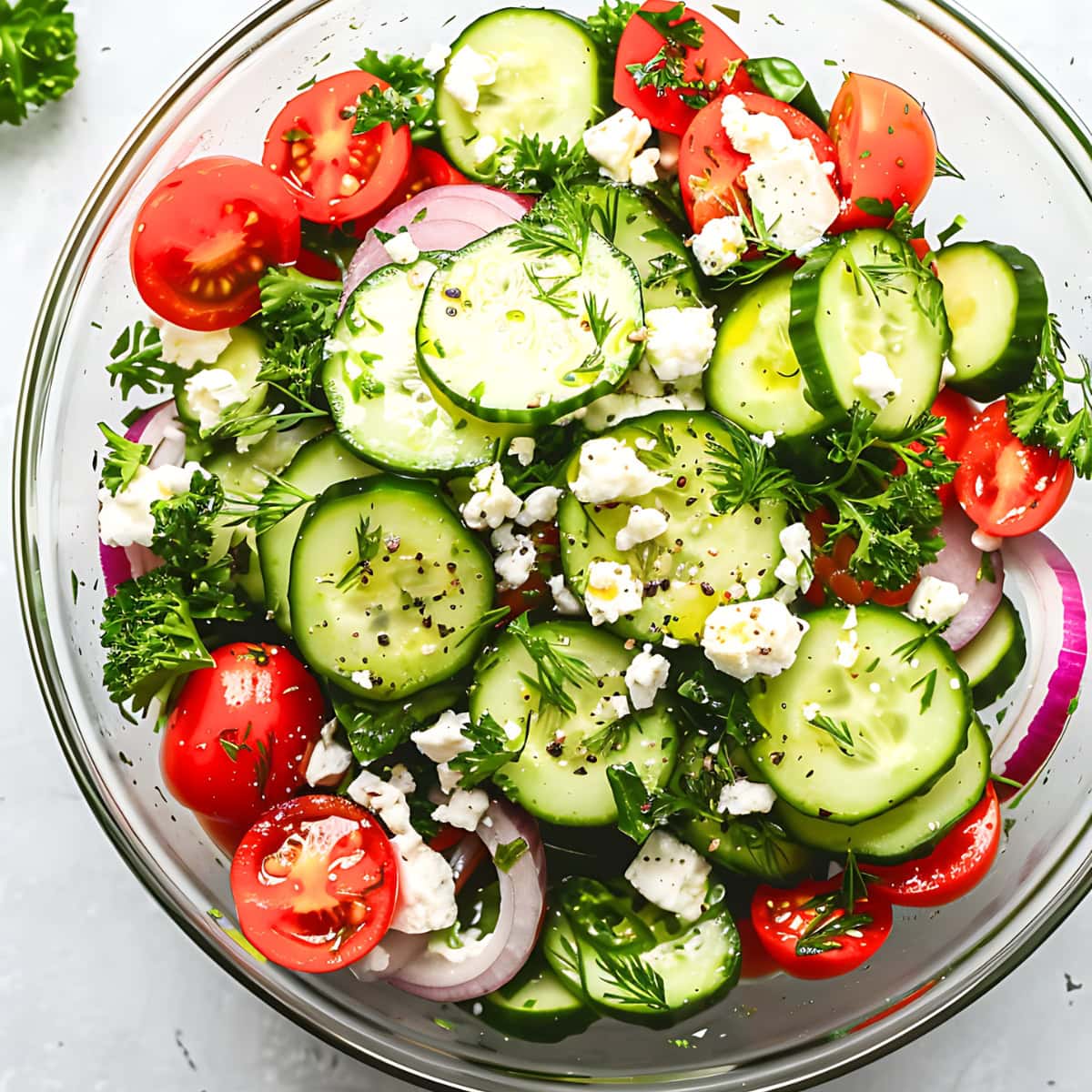 Cucumber tomato feta cheese salad tossed in a glass bowl. 