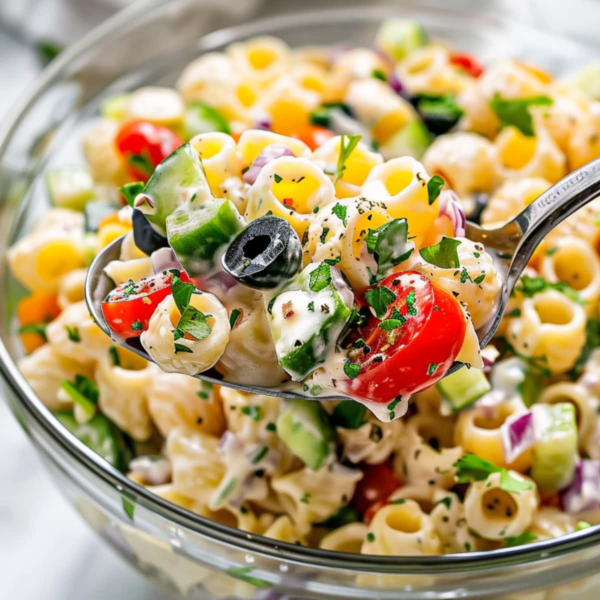 Ditalini pasta salad made with ditalini pasta, cherry tomatoes, cucumber, bell pepper, and red onion and creamy dressing served in a glass bowl.