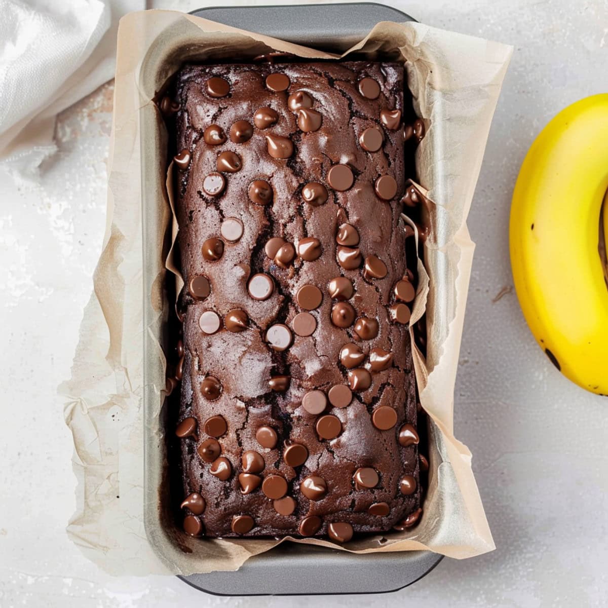 Loaf of chocolate banana bread in a loaf pan, top down view.