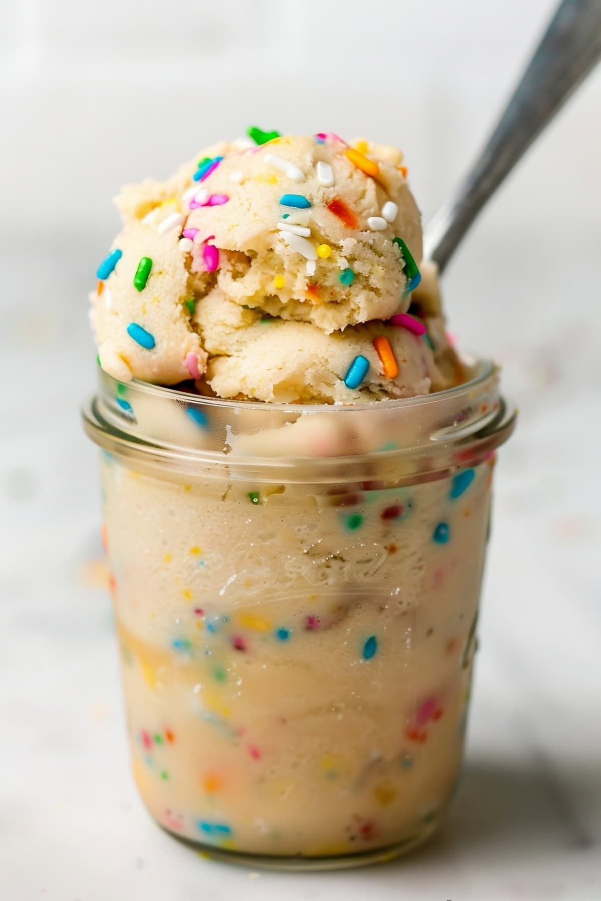 Homemade edible sugar cookie dough with sprinkles in a glass.