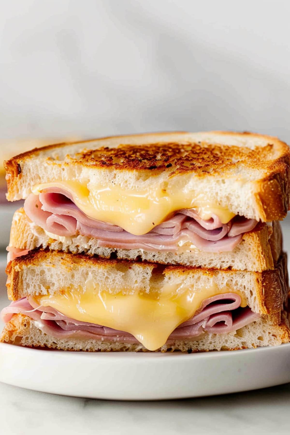 Close-up of a perfectly toasted grilled ham and cheese sandwich, with crispy edges and gooey cheese pulling apart.
