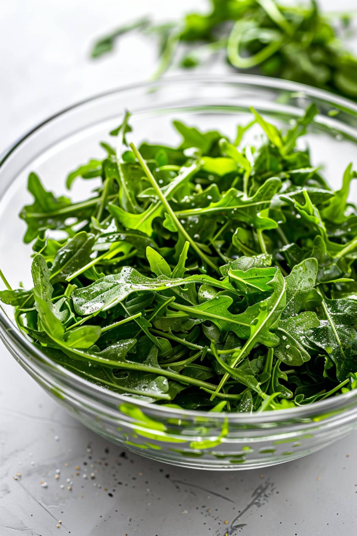 Fresh arugula leaves in a large glass bowl. 