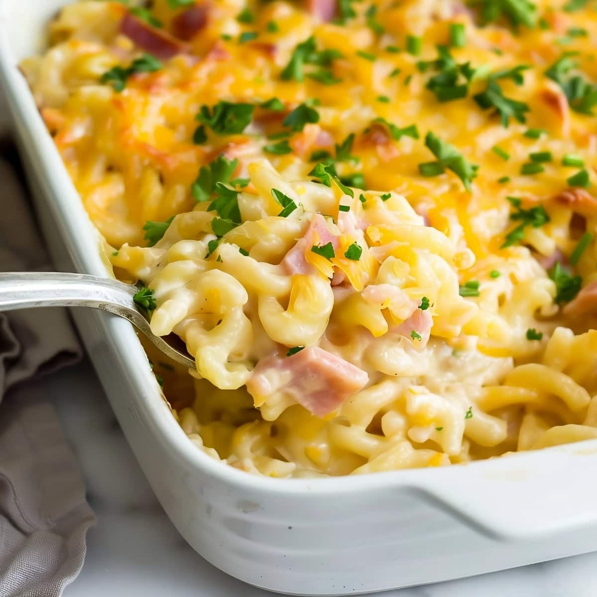 Homemade noodle casserole featuring diced hams and melted cheese.