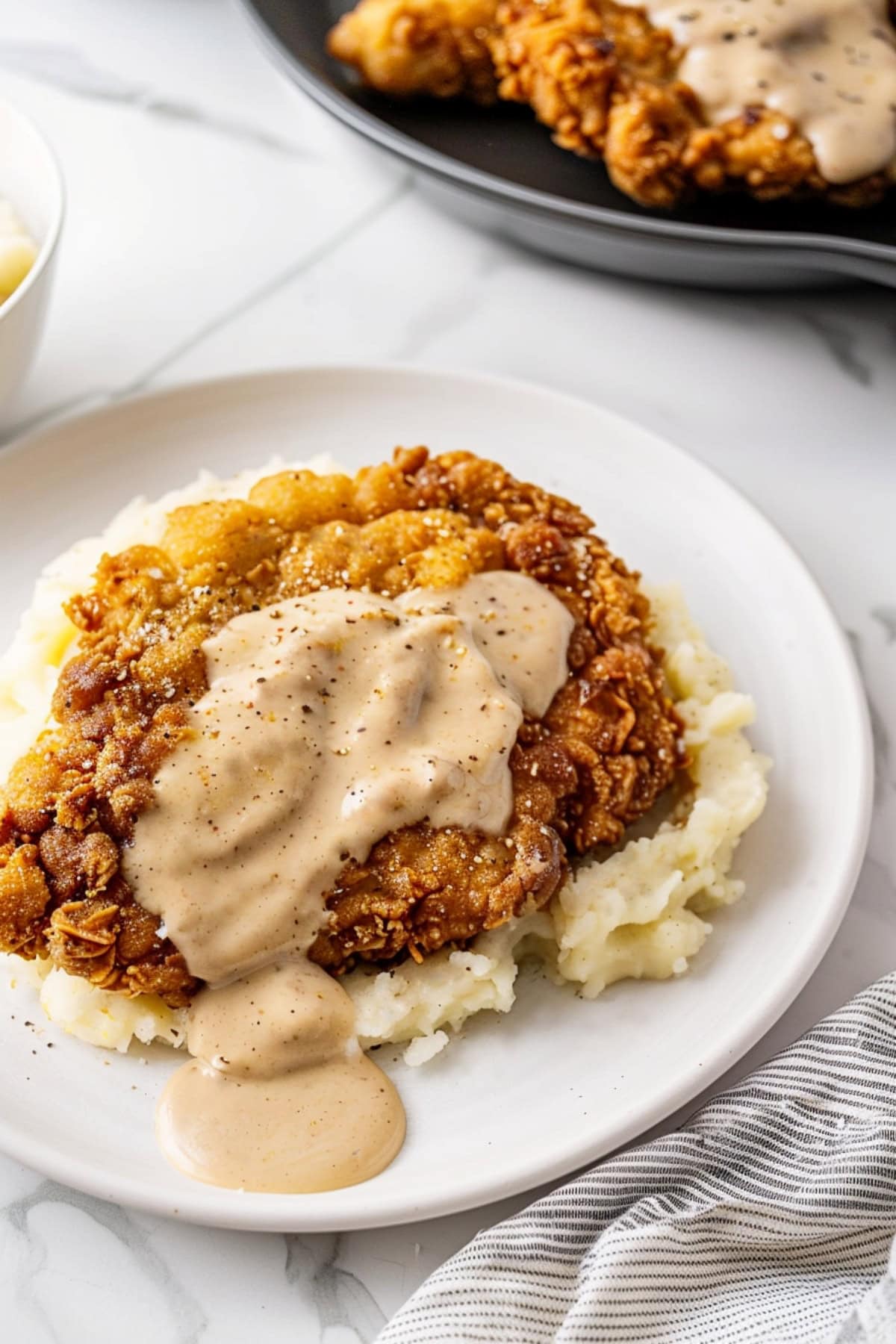 Homemade chicken fried steak with gravy in a bed of mashed potatoes.