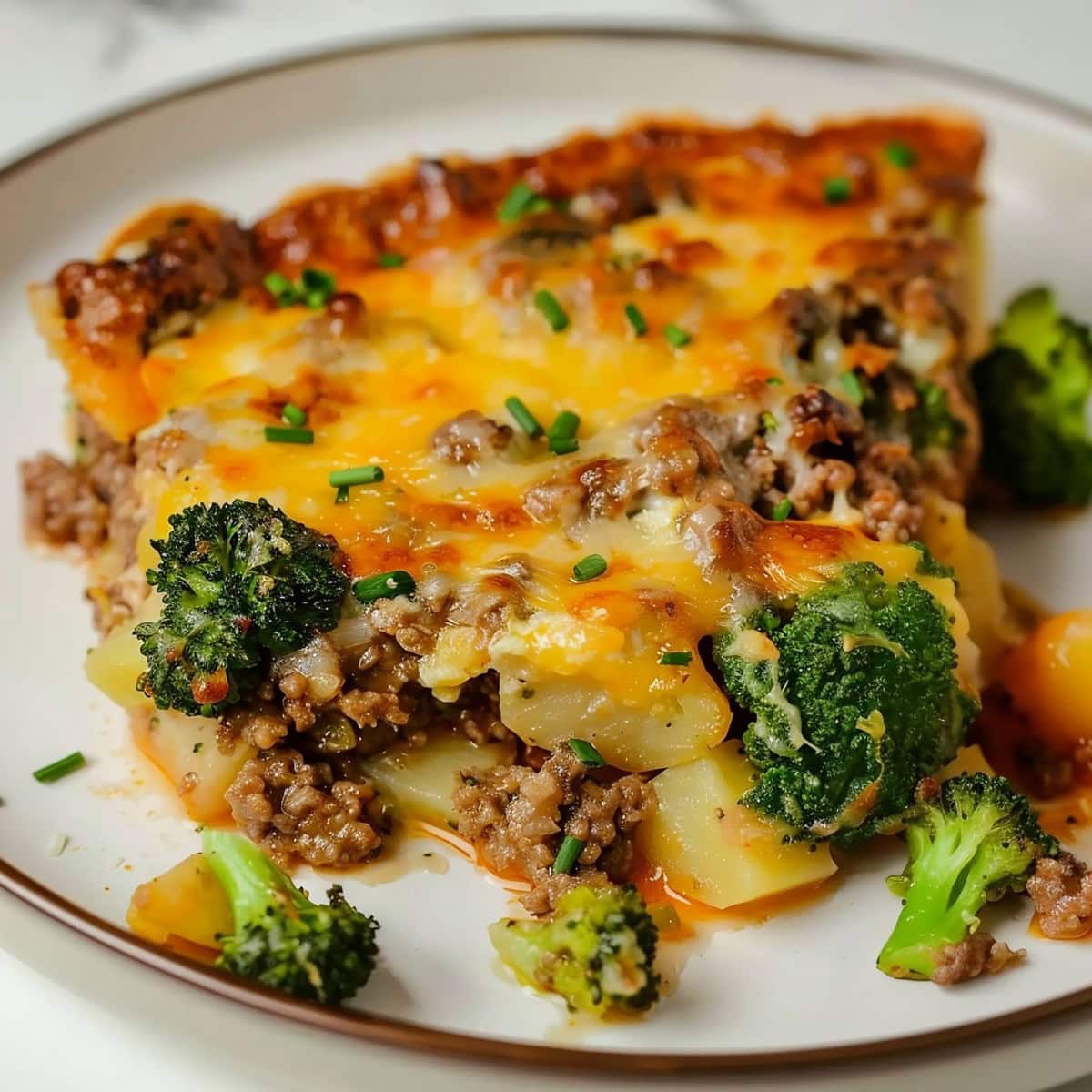 Super Close Up of Italian Sausage Breakfast Casserole Slice with Broccoli, Italian Sausage, Potatoes, and Cheese on a White Plate