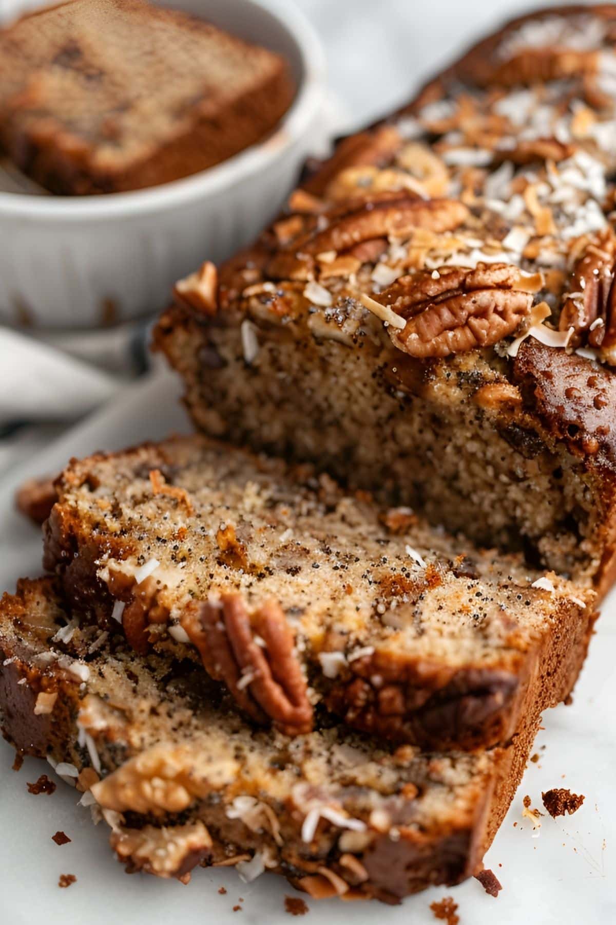 Close Up of Jamaican Banana Bread Loaf and Two Slices with Toasted Coconut and Toasted Pecans