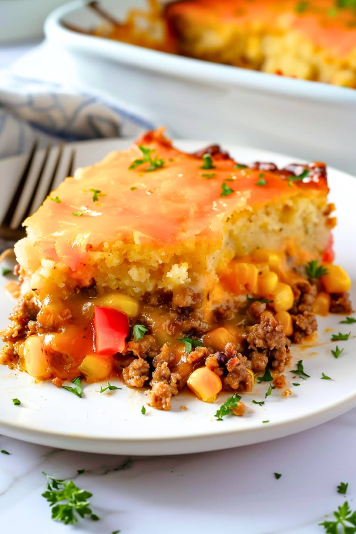 Square slice of Mexican cornbread casserole served on a white plate.