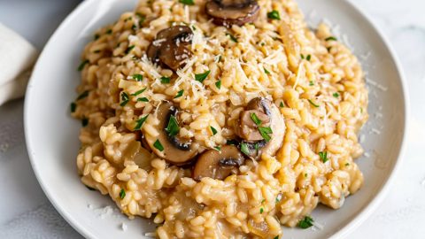 Close-up of a plate of mushroom risotto, showcasing the creamy texture, topped with parmesan and parsley.