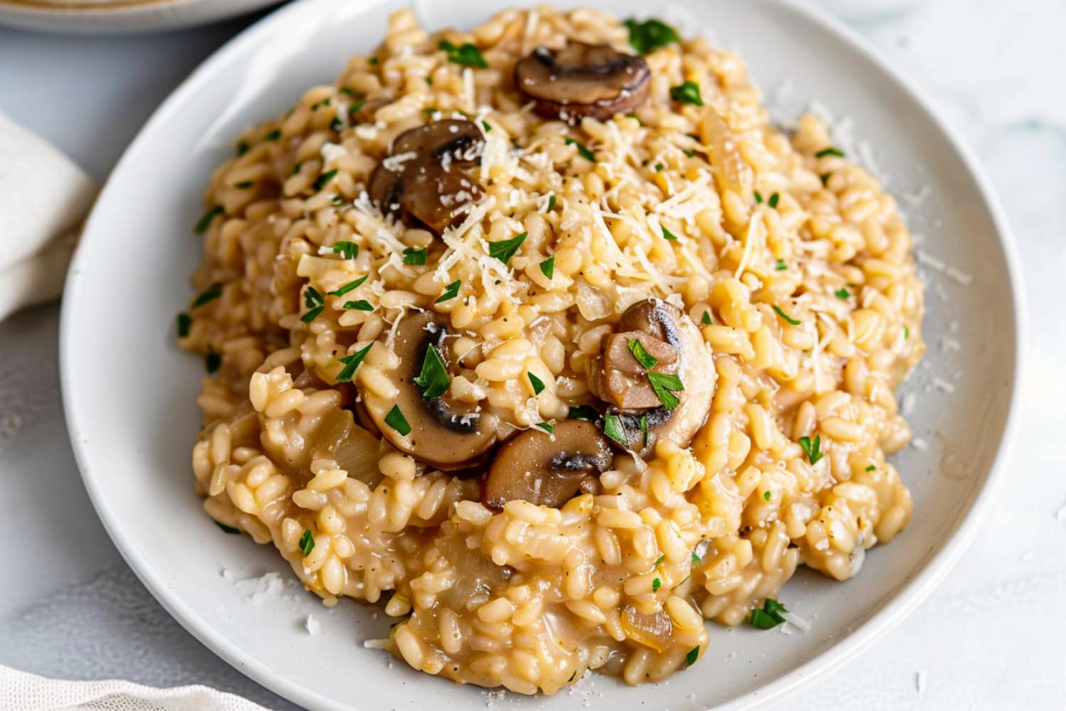 Close-up of a plate of mushroom risotto, showcasing the creamy texture, topped with parmesan and parsley.