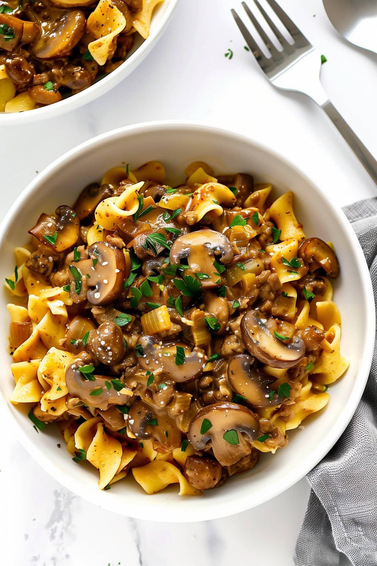 Mushroom stroganoff served in a white bowl, showcasing the creamy sauce with a fork ready to dig in.