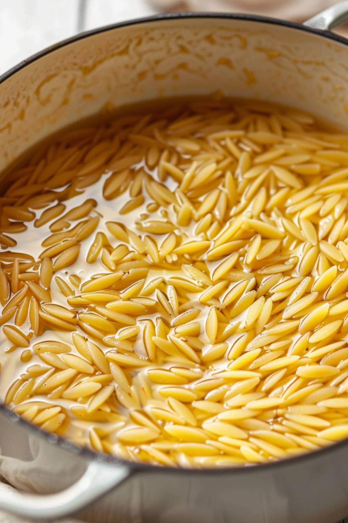 Orzo pasta in a pot cooked with broth.