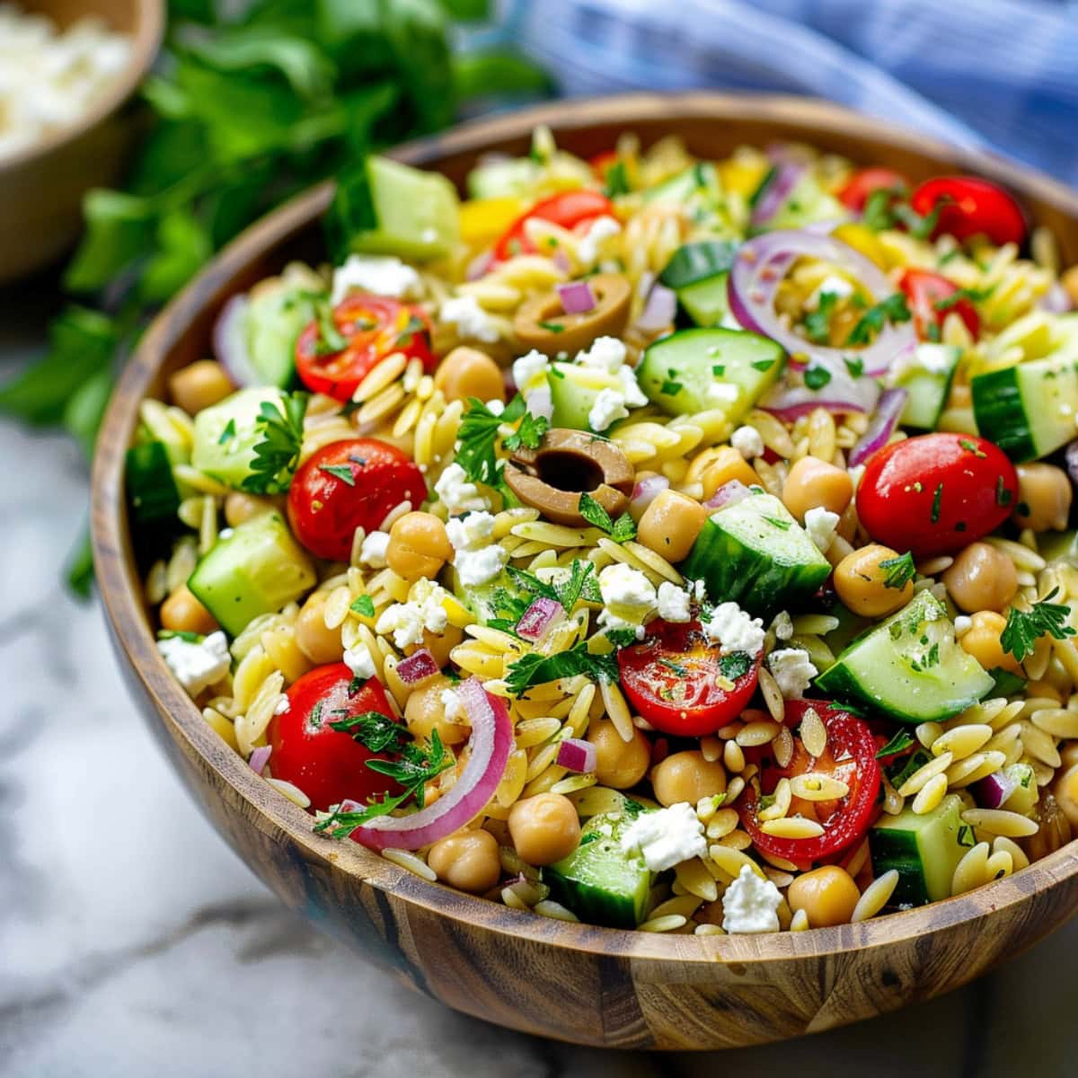 Orzo pasta salad served in a wooden bowl.