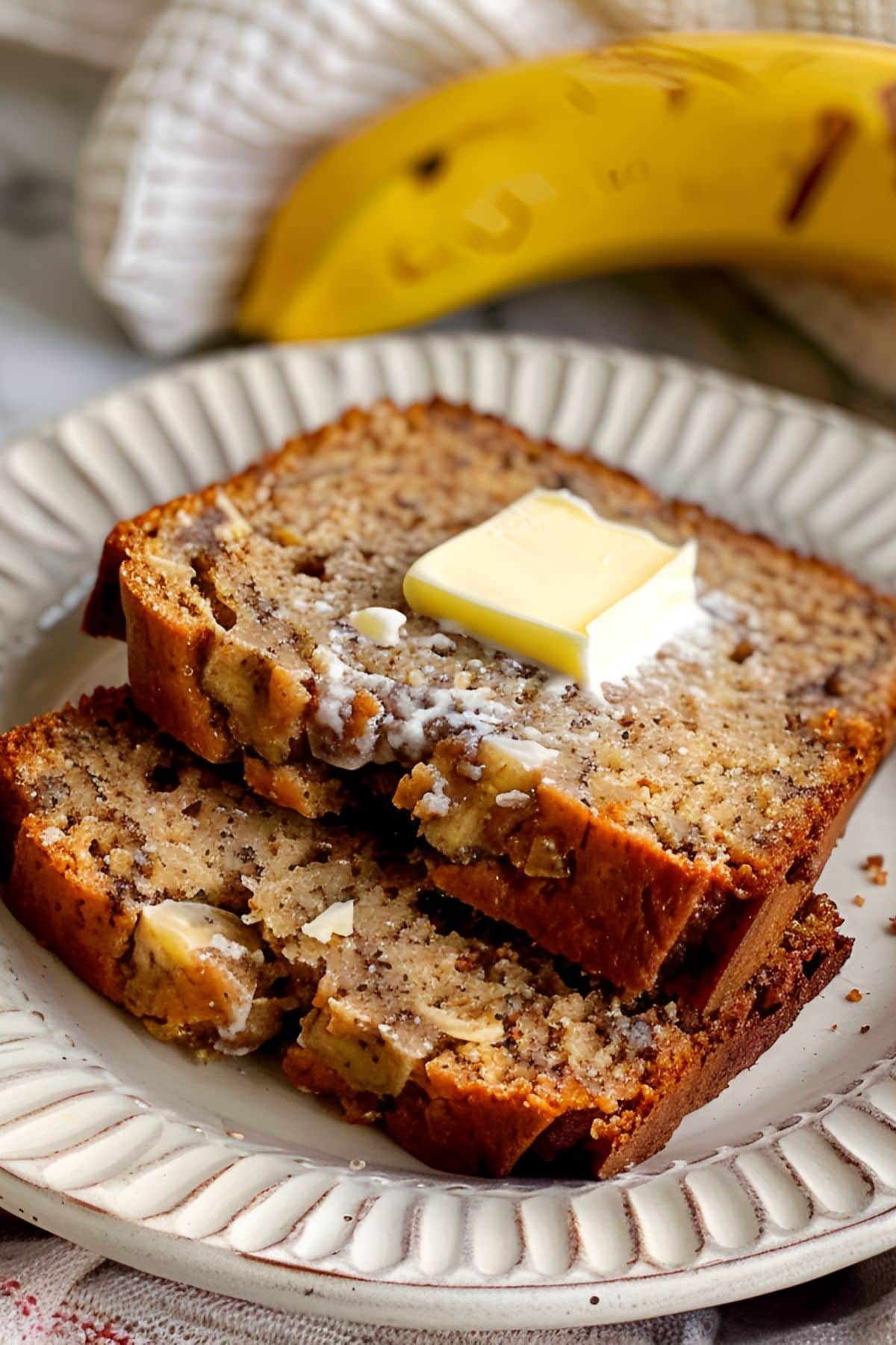 Super Close Up of Two Slices of Paula Deen Banana Bread with Butter on a White Plate