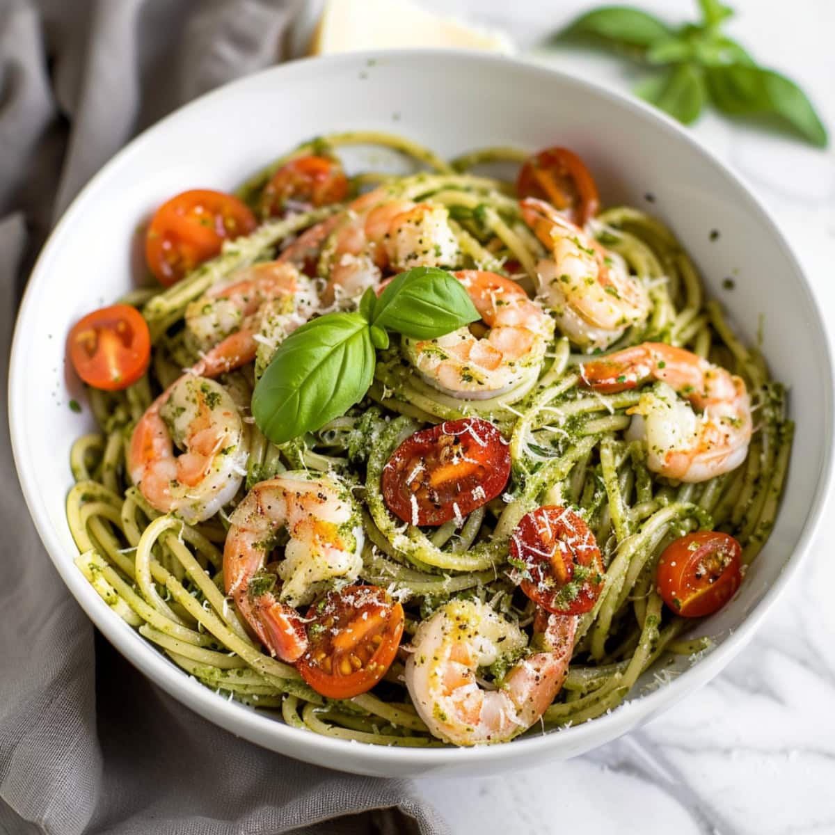 Spaghetti pasta with pesto, tomatoes and basil in a bowl.