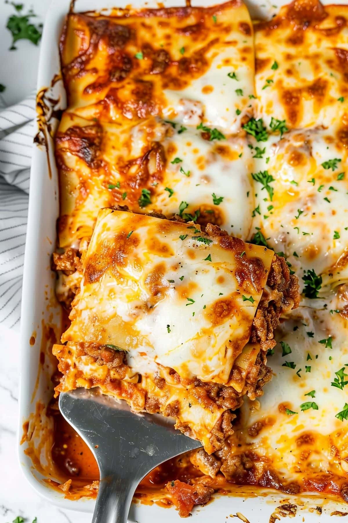 Top View of Prego Lasagna in a White Baking Dish with Spatula Holding Up a Slice