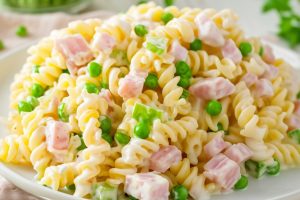 Rotini pasta, diced ham, frozen peas, and diced green pepper covered in dressing.