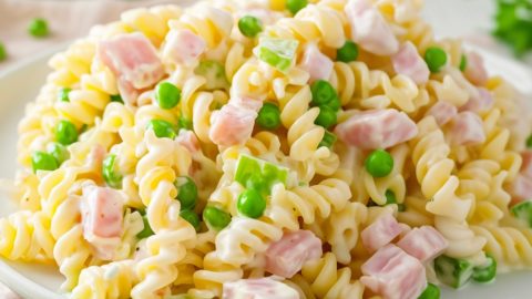 Rotini pasta, diced ham, frozen peas, and diced green pepper covered in dressing.