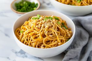 Quick and easy sesame noodles, featuring a rich, nutty sauce in a white bowl.