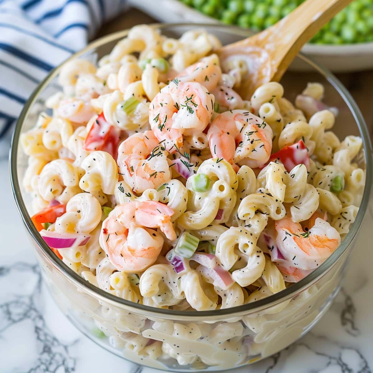 Creamy shrimp pasta salad tossed in a glass bowl. 