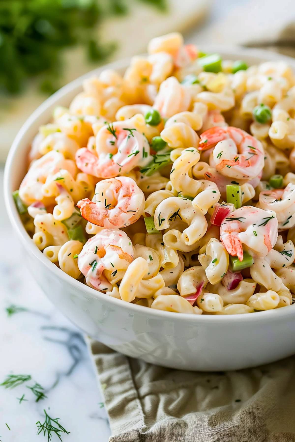 Shrimp pasta salad with juicy shrimp, crisp veggies, and a tangy dressing served on a white bowl.