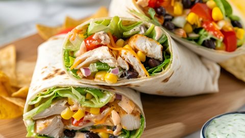 Southwest chicken wrap sliced in half served on a wooden board.