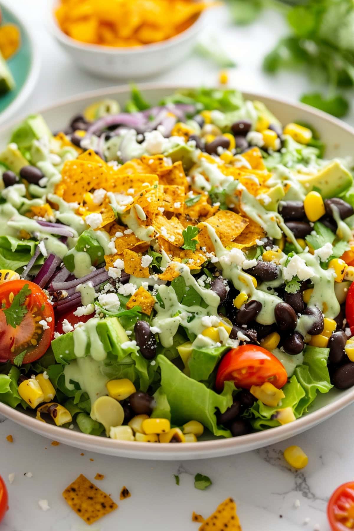  Romaine, hearty black beans, sweet corn, crunchy veggies, salty cotija, and creamy avocado and avocado dressing garnished with chopped tortilla on top.
