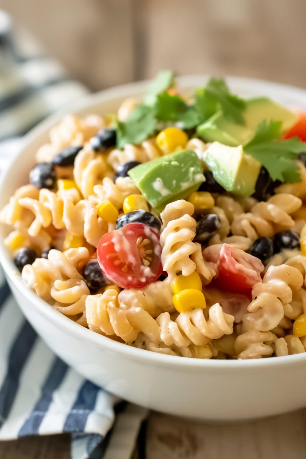 A heaping serving of Tex-Mex pasta salad in a bowl, showing off the mix of cherry tomatoes, black beans, and corn kernels.