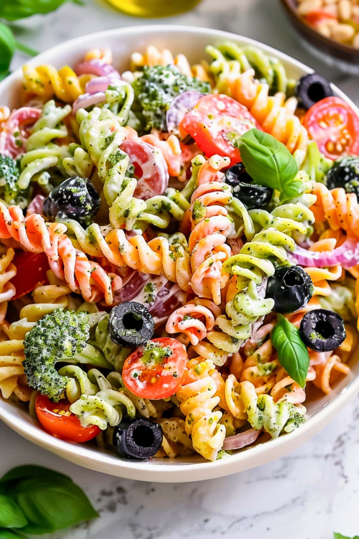 Bowl filled with serving of tricolor pasta coated in creamy caesar dressing.