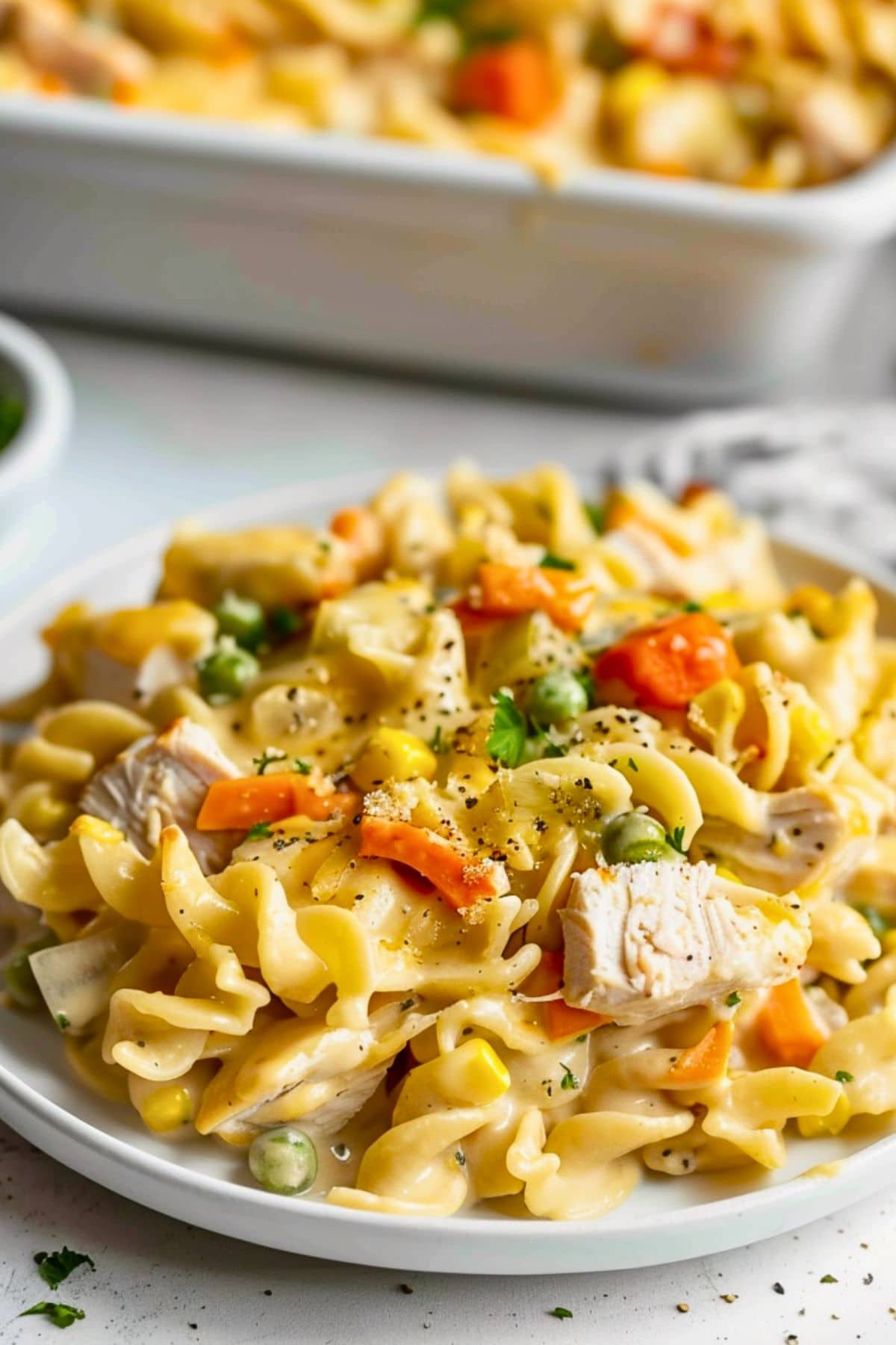 Serving of creamy turkey noodle casserole in a white plate.
