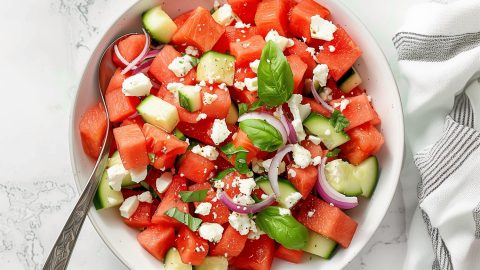 A bowl of freshly homemade watermelon salad featuring feta cheese, cucumbers and red onions.
