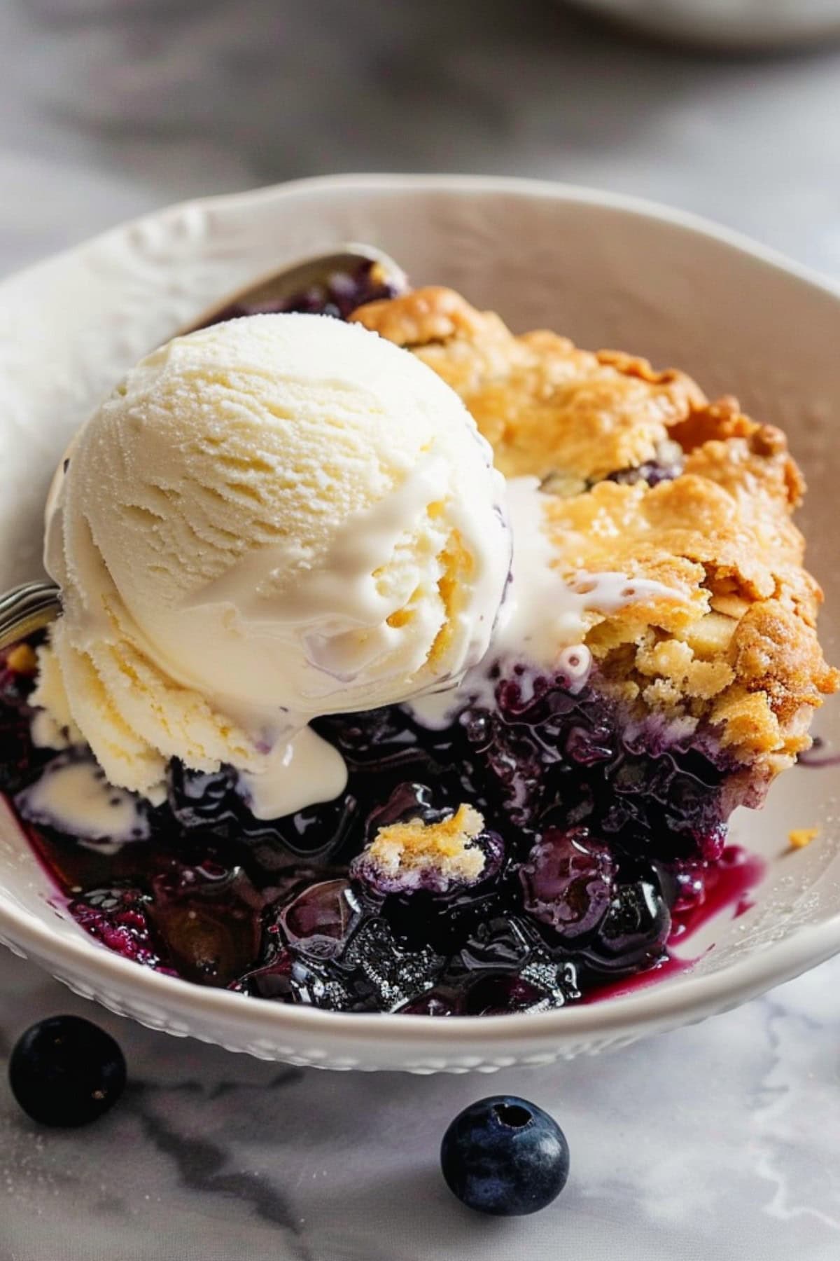 Homemade blueberry cobbler with a scoop of ice cream.