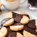 Chocolate-Dipped Shortbread Cookies on a Plate with Coffee in the Background