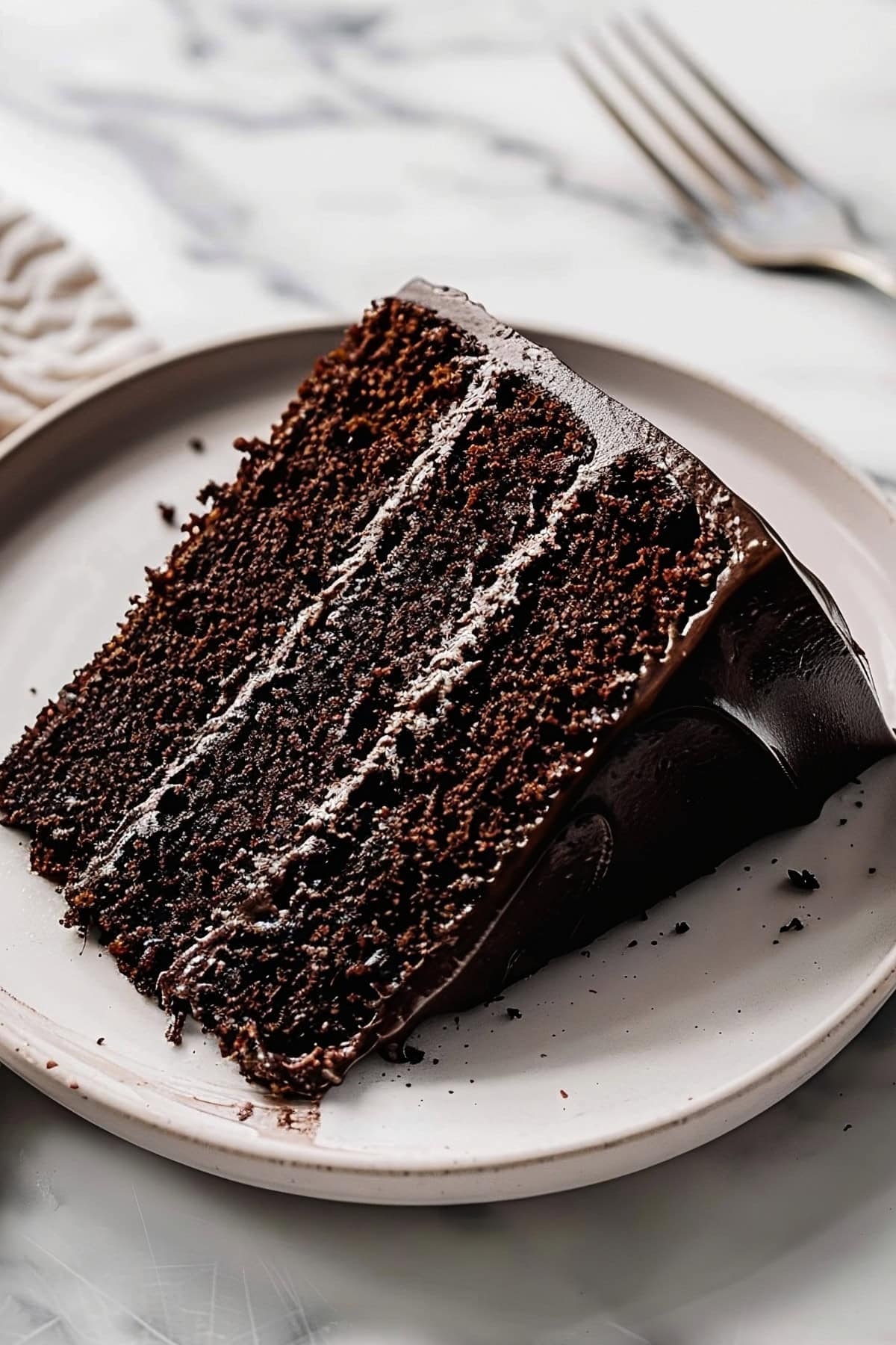 A chocolate fudge cake with a thick layer of chocolate icing and a smooth, fudgy texture inside.