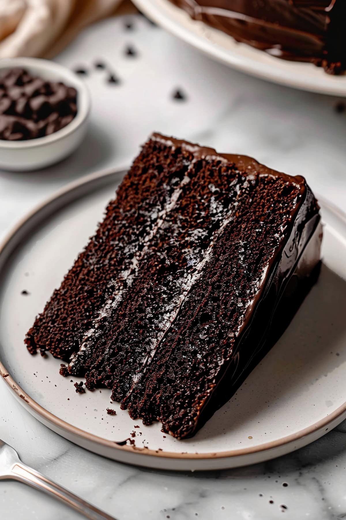 Soft and decadent chocolate fudge cake slice on a plate.