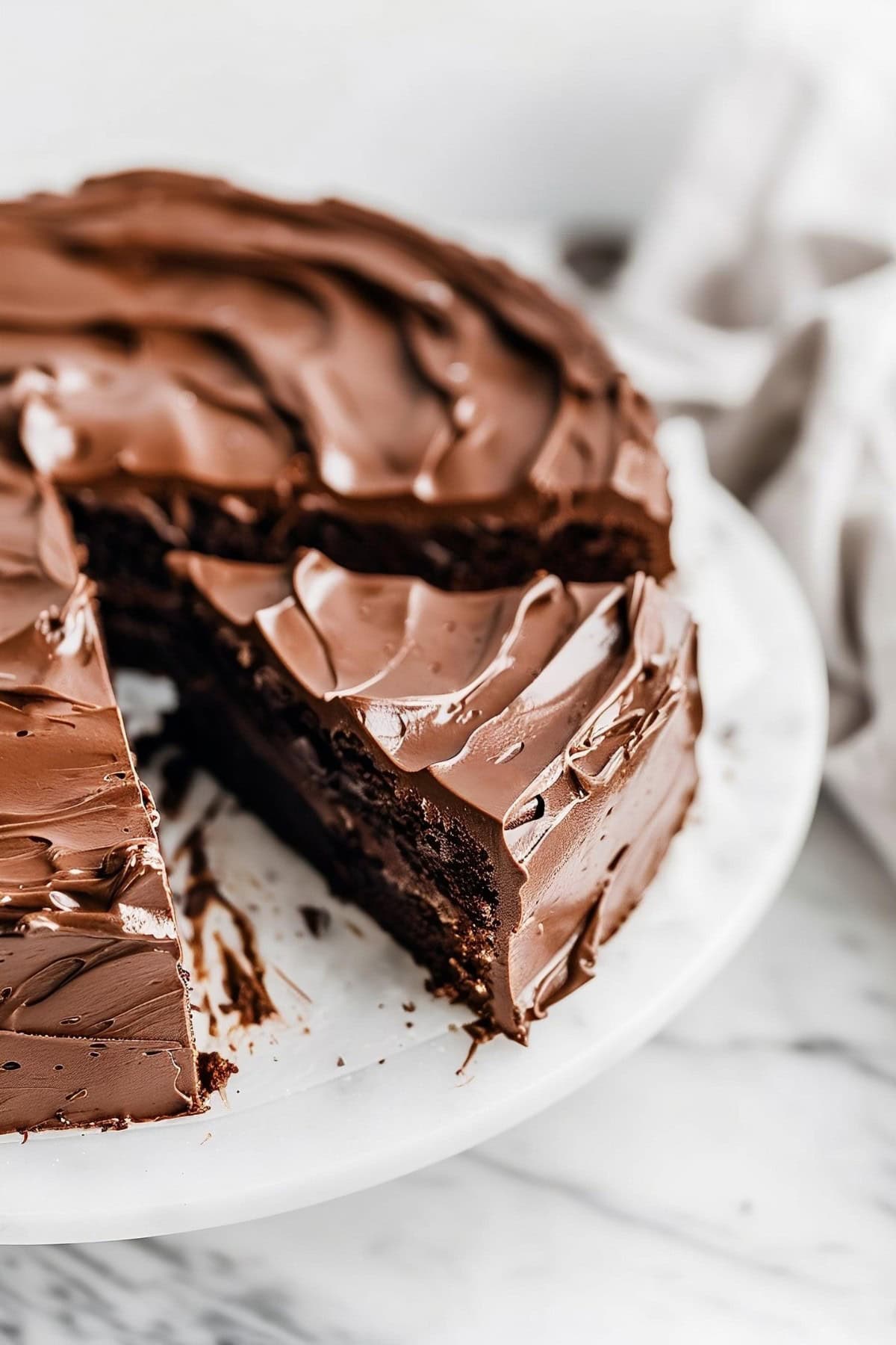 Sliced whole chocolate truffle cake in a cake tray.