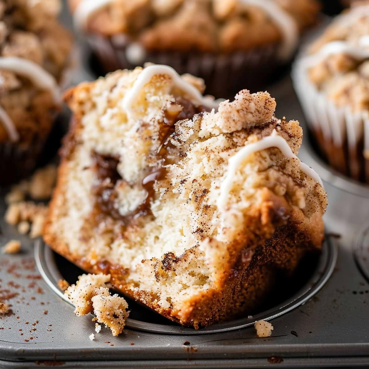 Coffee Cake Muffins, broken in half on a muffin tray.